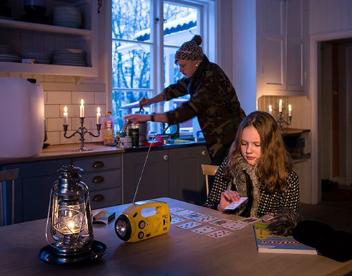 Foto på familj som har strömavbrott och bland annat spelar kort