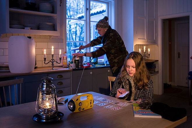 Foto på familj som har strömavbrott och bland annat spelar kort