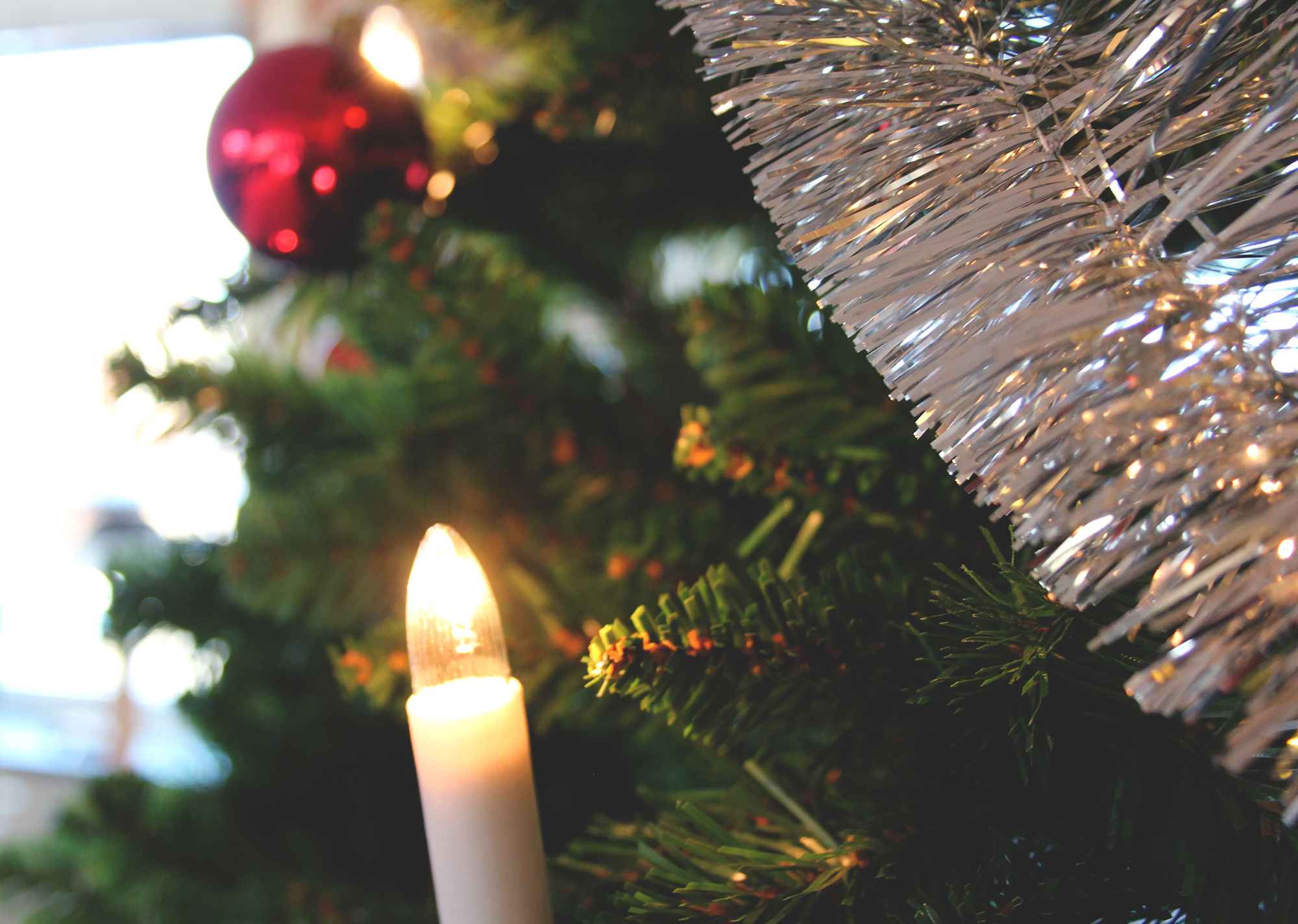 Närbild på julgranskula och julgransljus i en julgran.